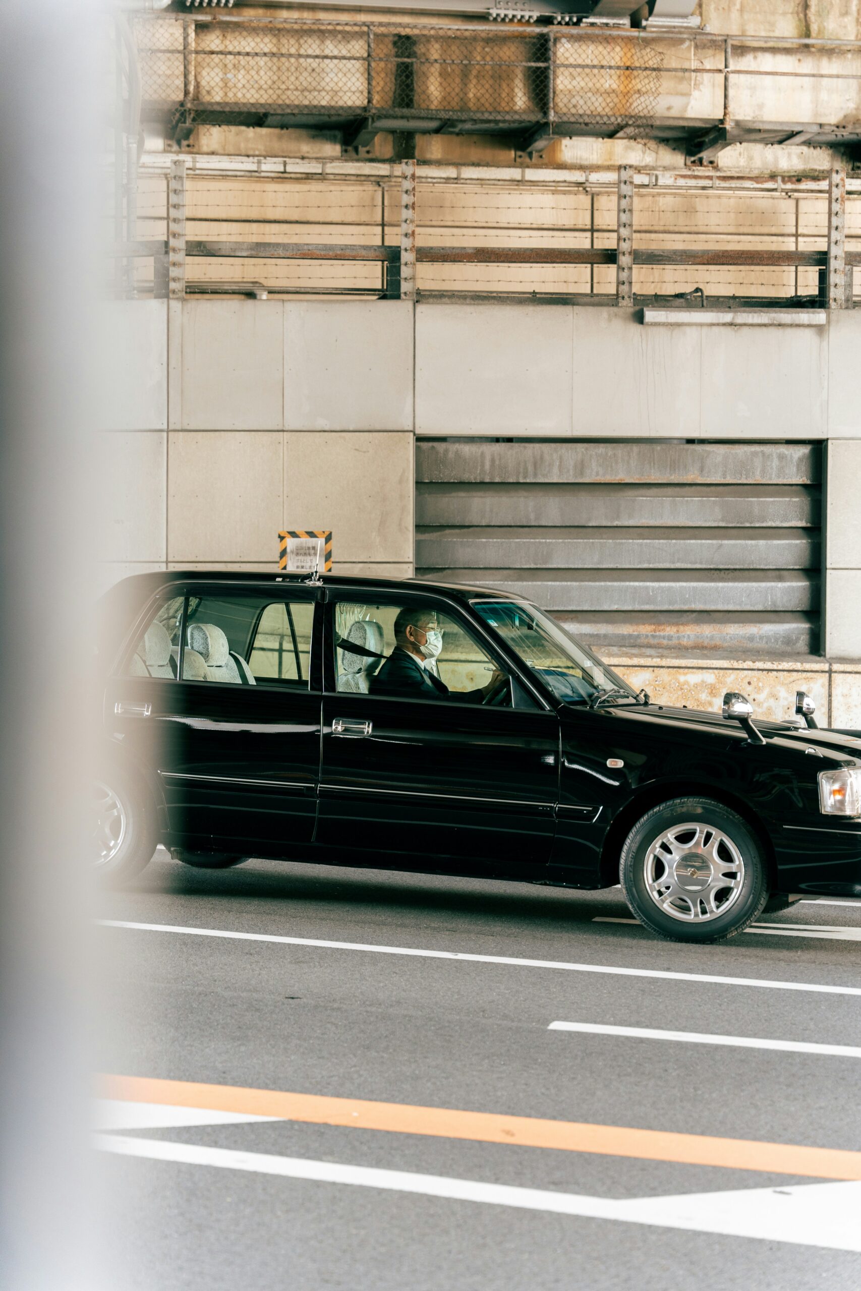 a black car driving a black car driving down a street next to a tall building